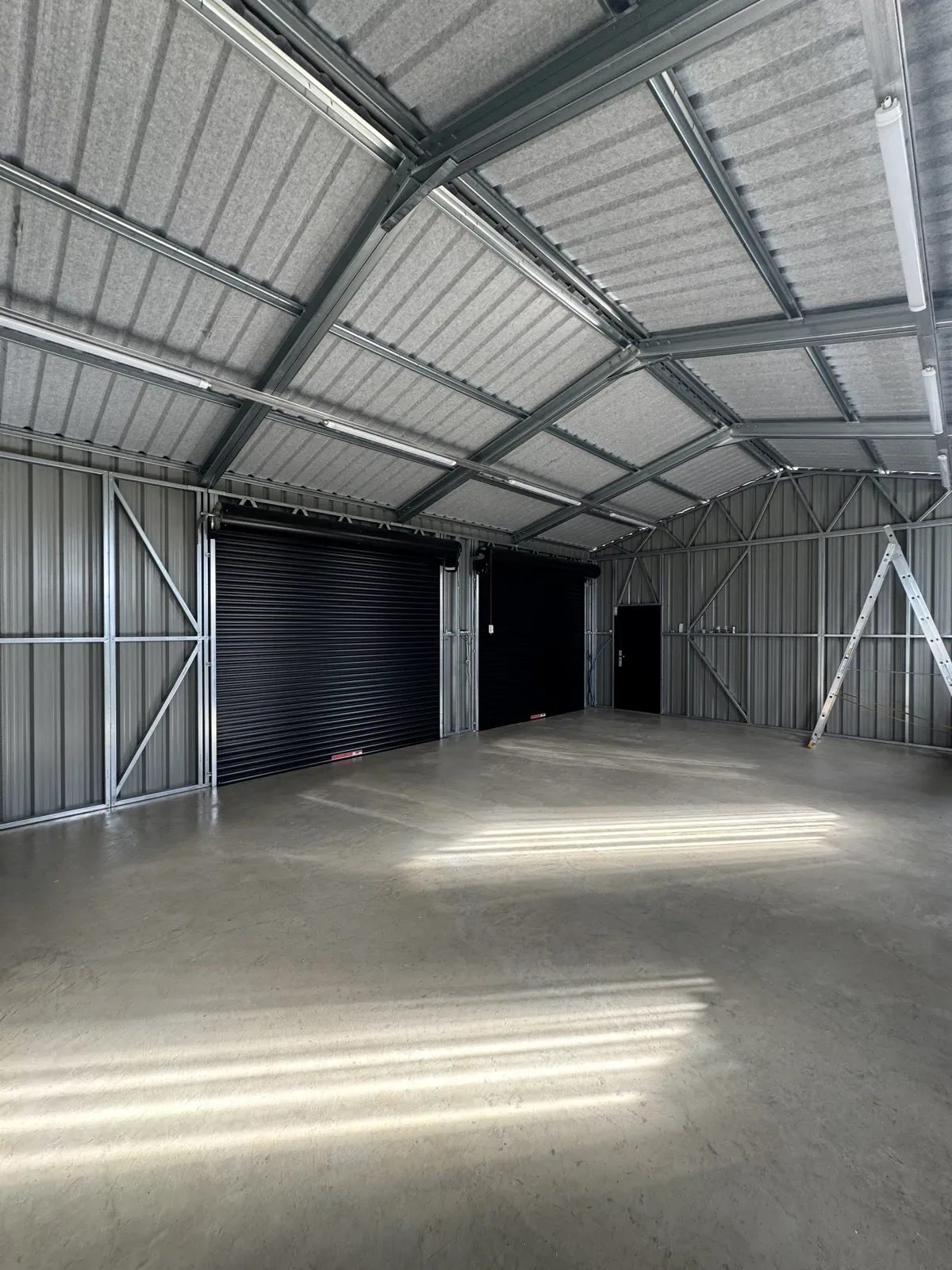 Inside a large steel workshop with roller doors